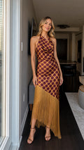 Front view of woman wearing brown polka dot halter maxi dress with fringe hem