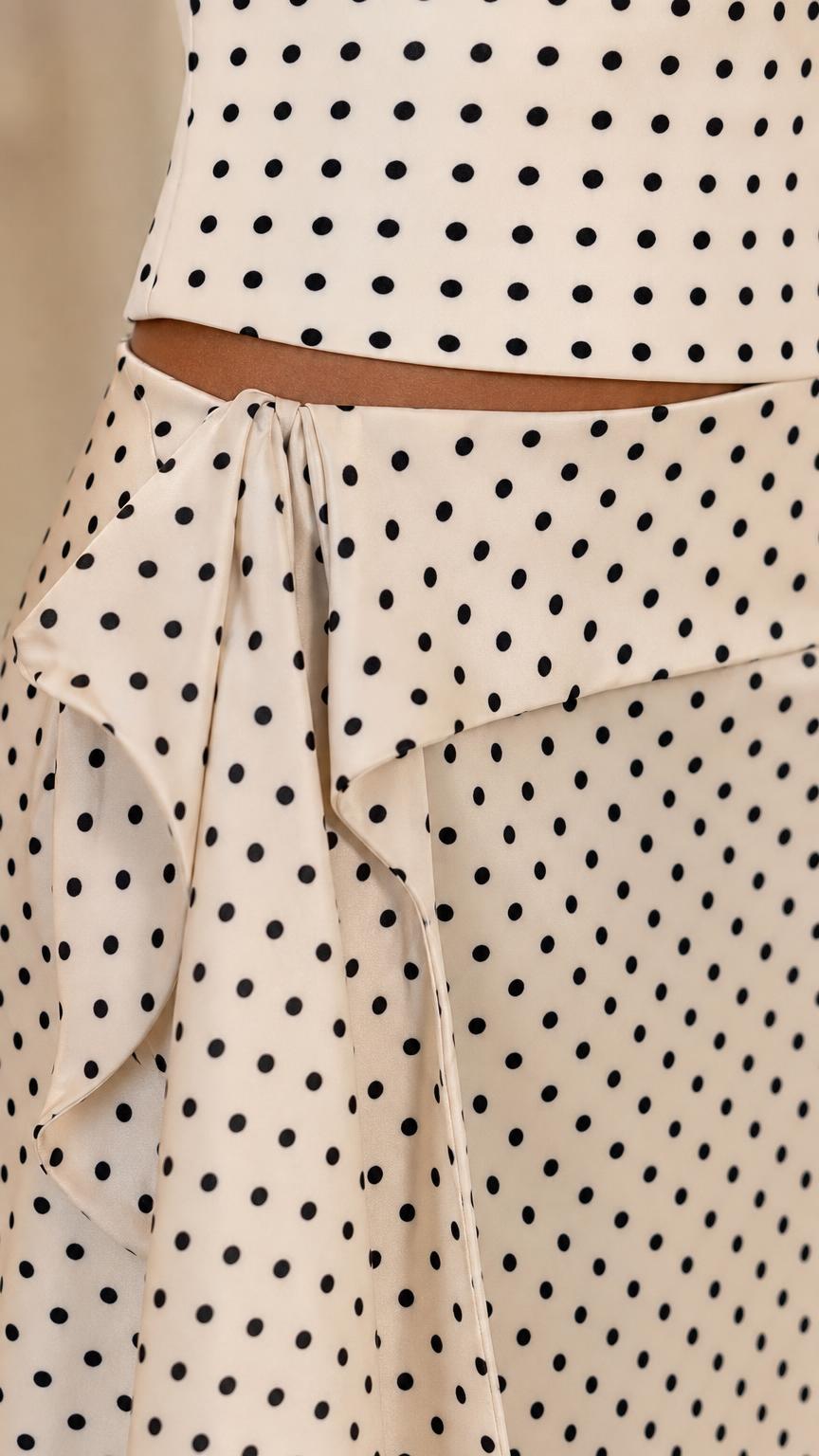 Close-up detail of the side tie and ruffle accent on the polka dot maxi skirt